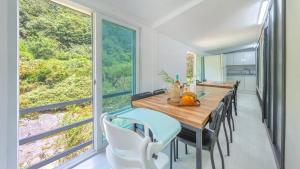a dining room with a table and chairs and large windows at Gapyeong Wood Valley Kids Pension in Gapyeong