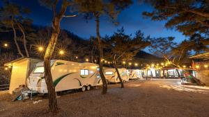 eine Reihe von Wohnmobilen, die nachts auf einem Parkplatz geparkt sind in der Unterkunft Yangpyeong Smile Caravan Pension in Yangpyeong