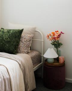 una cama con un jarrón de flores sobre una mesa con una lámpara en Tamar Views, en Inveresk