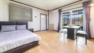 a bedroom with a bed and a desk and windows at Gapyeong Etoile Pension in Gapyeong +4 photos