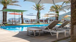 un gruppo di sedie e ombrelloni accanto a una piscina di Geoje Break Time Pension a Geoje