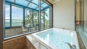 una vasca da bagno in una stanza con una grande finestra di Geoje Break Time Pension a Geoje