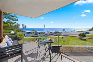ポート・マッコリーにある6 58 Pacific Drive - Beachfront modern apartmentの海の景色を望むバルコニー(テーブル、椅子付)