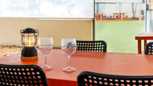 two wine glasses sitting on a table with a lantern at Daebudo green beach Pension in Ansan