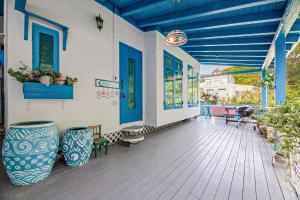 un porche con puertas azules, sillas y plantas en Ganghwa Picnic Pension, en Incheon
