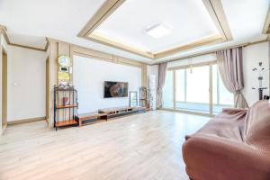 a living room with a couch and some windows at Samcheok Greenhyang Pension in Samcheok