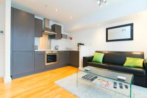 a living room with a black couch and a kitchen at Mitchell Street Glasgow Apartment in Glasgow