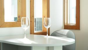 dos copas de vino sentadas en una mesa blanca con una silla en Ganghwa Hanabi Pension, en Incheon