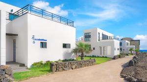 a white building with a stone wall next to it at casadelfino in jeju in Seogwipo