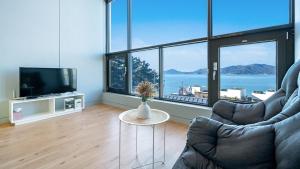 a living room with a couch and a tv and a table at Namhae Byeol grigo namhae Pension in Namhae