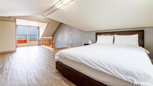a bedroom with a large bed and a large window at Jeju Badagreen Pension in Jeju