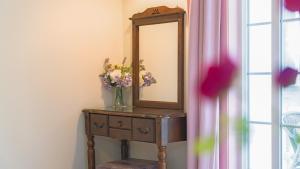 a mirror on a table with flowers in a vase at Ganghwa Daeun pension in Incheon