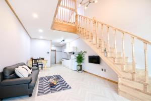 a living room with a couch and a staircase at Gangneung Raon Pension in Gangneung