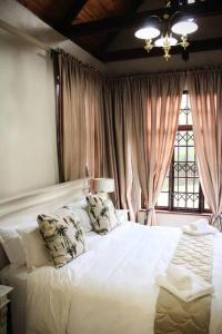 Un dormitorio con una cama blanca con almohadas y una ventana. en Clarens Charm, en Clarens
