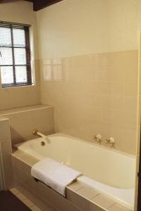 Una bañera blanca en un baño con ventana. en Clarens Charm, en Clarens 21 fotos más