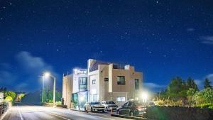 un edificio con auto parcheggiate di fronte ad esso di notte di Jeju ChunJaNe Pension a Seogwipo