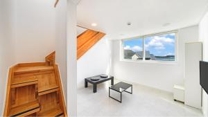 ein Wohnzimmer mit einer Treppe und einem Fenster in der Unterkunft Gangneung Lacblanc Pension in Gangneung + 13 Fotos