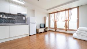 a kitchen with white cabinets and a large window at jeju ondamhouse pension in Jeju