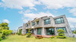 an exterior view of a large stone building with benches at jeju ondamhouse pension in Jeju