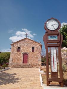 un orologio davanti a un edificio con una chiesa di Área 51 Hospedaria - STL a São Thomé das Letras