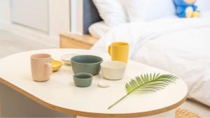 a white table with four cups and a plant on it at Gapyeong Daengdaengi Dog Pension Silver in Gapyeong