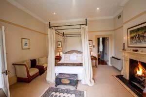 a bedroom with a canopy bed and a fireplace at Hacklewood Hill Country House in Port Elizabeth