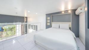 a bedroom with a white bed and a large window at Gapyeong Villajia Spa Pension in Gapyeong