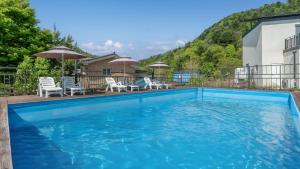 a blue swimming pool with chairs and umbrellas at Gapyeong Villajia Spa Pension in Gapyeong