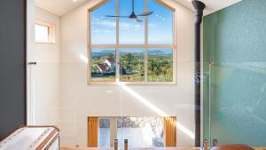 a bathroom with a window and a shower with a glass door at Jeju Sogilrian974 Pension in Jeju