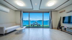 Una sala de estar con un sofá y vista al mar. en Yeosu Baraboda Ocean View Pension, en Yeosu