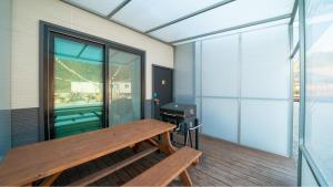 a balcony with a wooden bench and a grill at GaPyeong Yeoldudal Spapension&Camping in Gapyeong