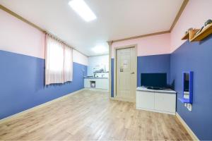 an empty room with blue walls and a television at Sokcho Dderak Pension in Sokcho +4 photos