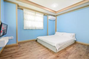 a blue bedroom with a bed and a window at Sokcho Dderak Pension in Sokcho