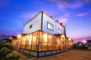 a large building with glass windows in a parking lot at Sokcho Dderak Pension in Sokcho