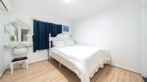 a white bedroom with a bed and a mirror at Ganghwa Giverny Spa Pension in Incheon