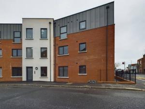 an empty street next to a brick building at Cozy 2-Bed Belfast Apartment in Belfast
