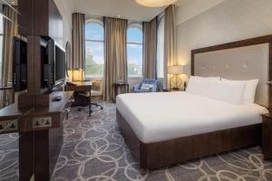 a hotel room with a large bed and a desk at Glasgow Grosvenor Hotel in Glasgow