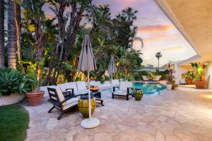 an outdoor patio with an umbrella and chairs and a pool at Edwin by AvantStay Hollywood Hills Luxury Pool in Los Angeles