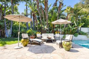 a patio with chairs and umbrellas next to a pool at Edwin by AvantStay Hollywood Hills Luxury Pool in Los Angeles