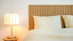 a bed with a white pillow and a lamp at Chuncheon Lio Pension in Chuncheon +2 photos