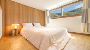 a bedroom with a large bed with a large window at Chuncheon Lio Pension in Chuncheon