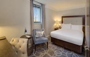 a hotel room with a bed and a chair at Glasgow Grosvenor Hotel in Glasgow