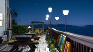 a deck with tables and chairs on a balcony at night at Ganghwa White Stone Pension in Incheon