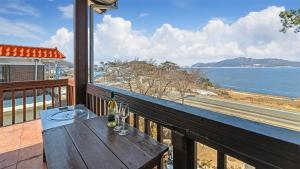 un balcón de madera con una mesa con copas de vino. en Ganghwa Badabit pension, en Incheon 8 fotos más