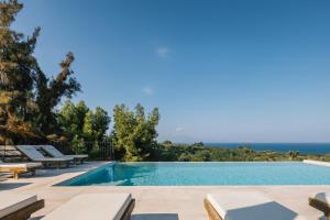 una piscina con sedie a sdraio accanto a una piscina di Ilyessa Cottages a Méson Yerakaríon