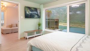 a bedroom with a bed and a large window at Danyang greennarae dokche poolvilla Pens in Danyang
