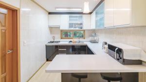 a kitchen with a large white counter and a sink at jeju oceancliffcottage in Jeju +6 photos