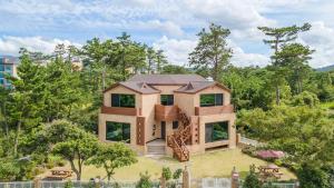 a house on top of a field with trees at jeju oceancliffcottage in Jeju
