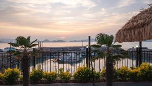 a fence with palm trees in front of a marina at Yeosu Wayo Ocean View Pension in Yeosu +3 photos