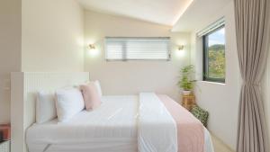 a white bedroom with a bed and a window at gyeongju daol dokchae pension in Gyeongju